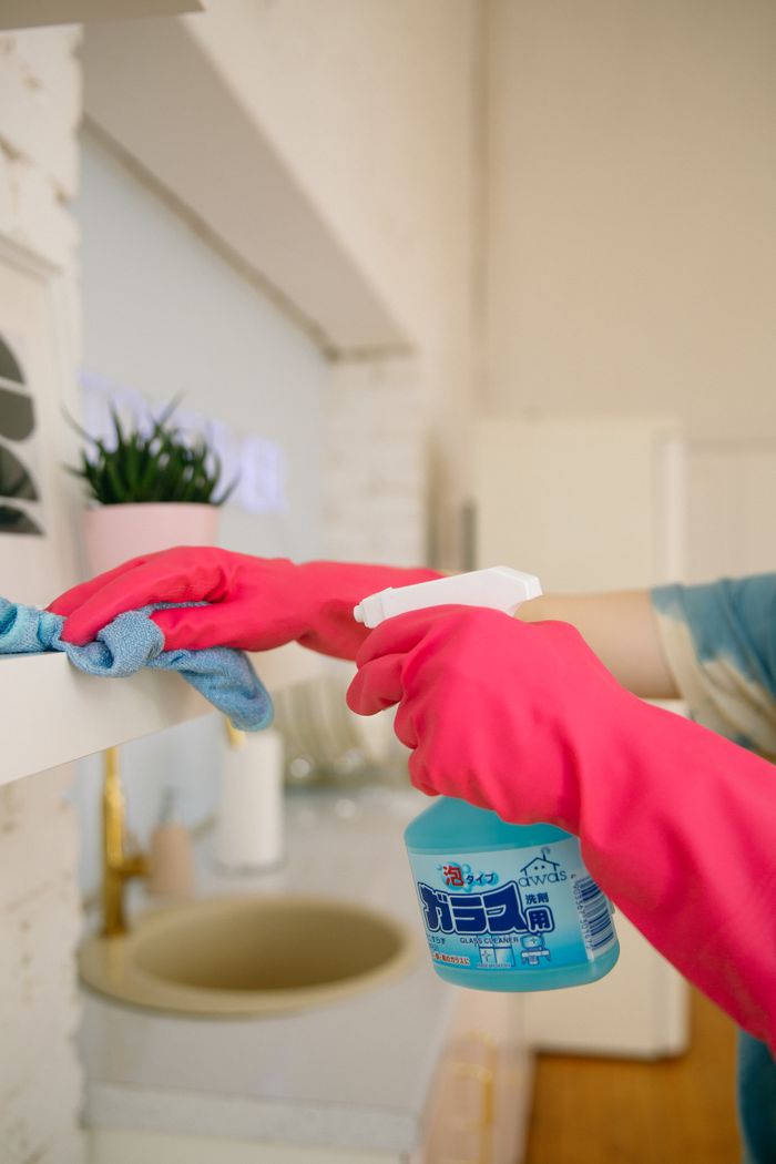 project-03-b Person using spray bottle and cloth for cleaning a kitchen shelf, ensuring hygiene and cleanliness.
